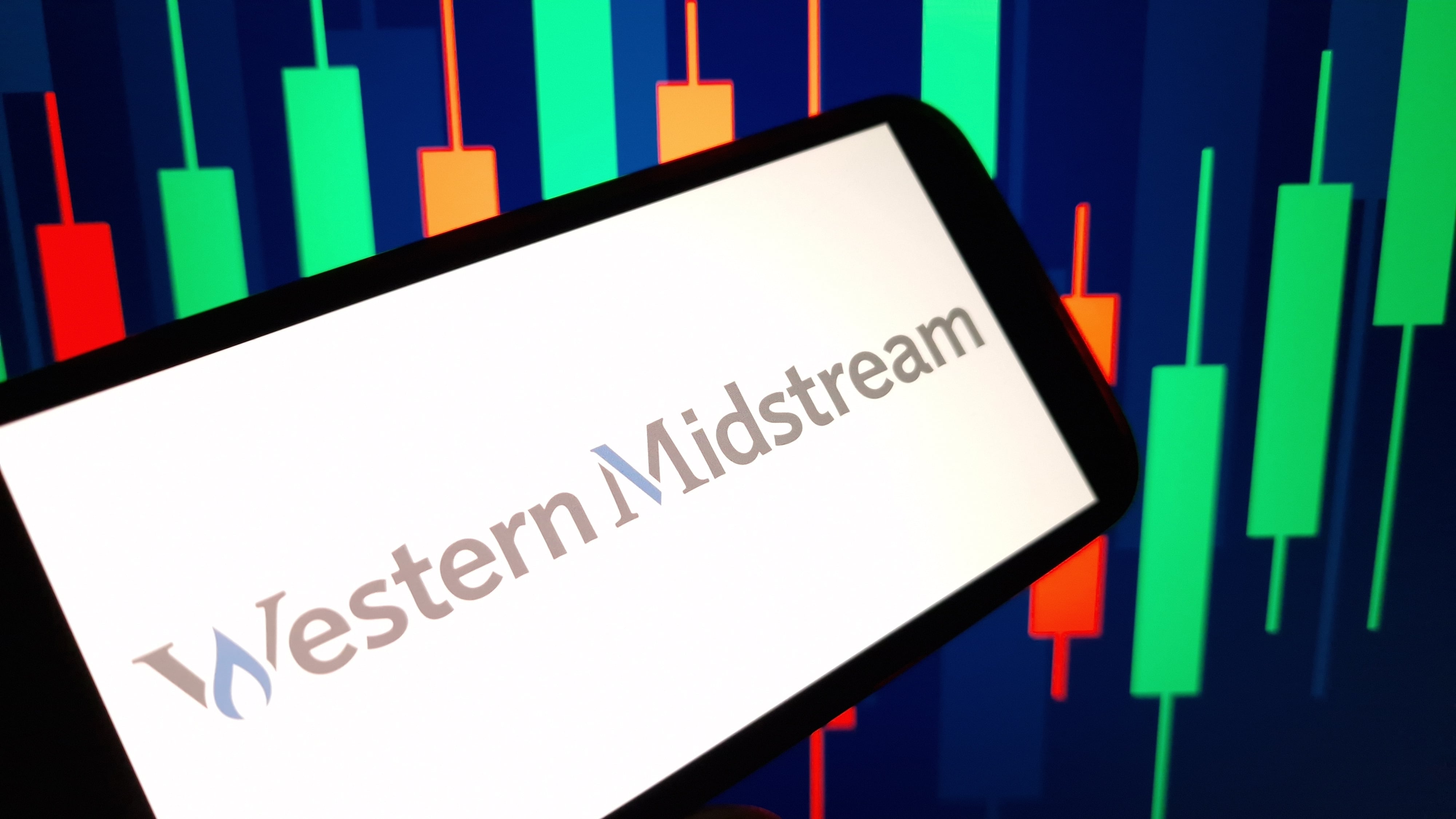 Western Midstream logo on a smart phone in front of a graph background.