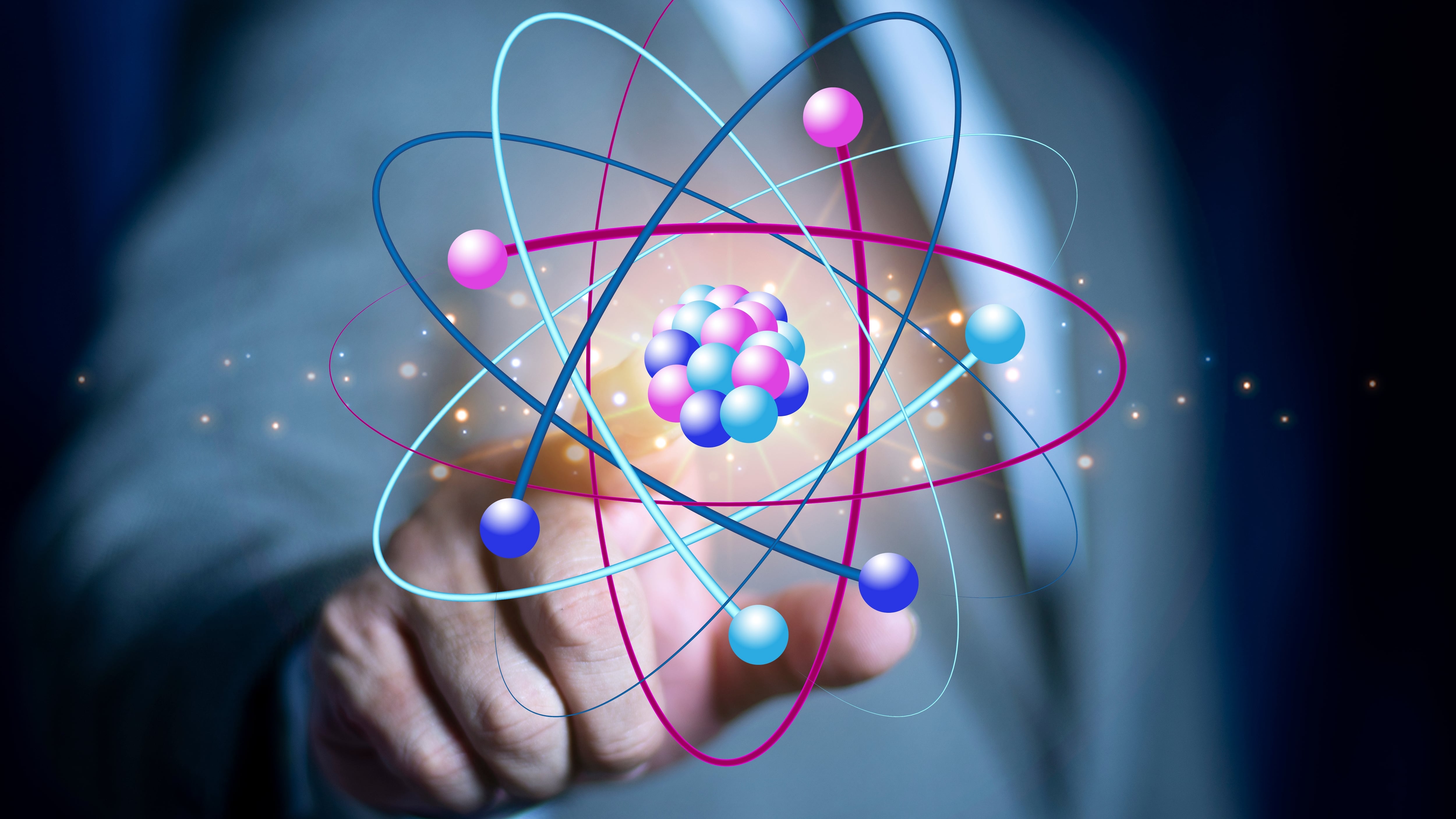 A business man with an outstretched hand reaching towards a graphic of an atom. Representative of nuclear energy research and development.