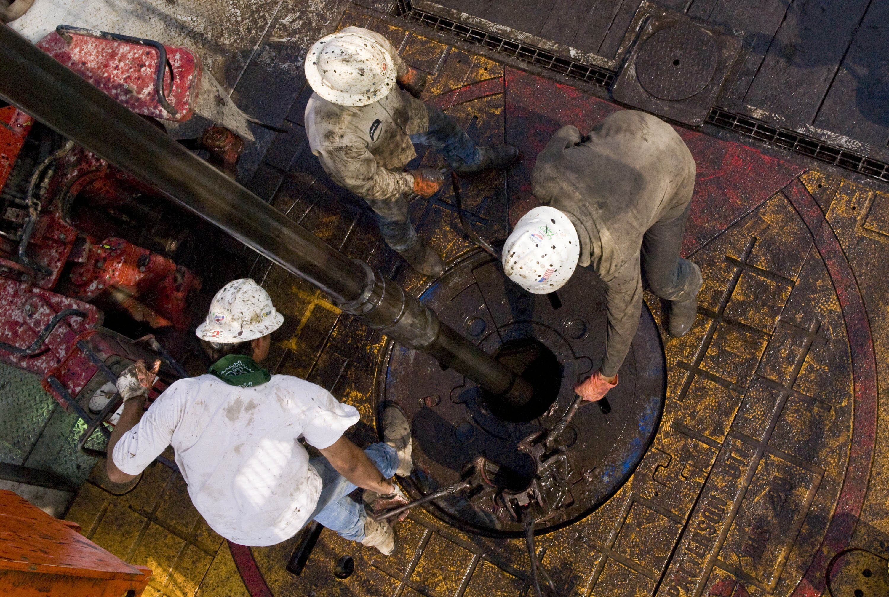 Patterson UTI Drilling Co. floorhands move a drill pipe collar as pipe is removed from a natural gas well being drilled in the Eagle Ford shale in Karnes County, Texas, U.S., on Tuesday, June 22, 2010.