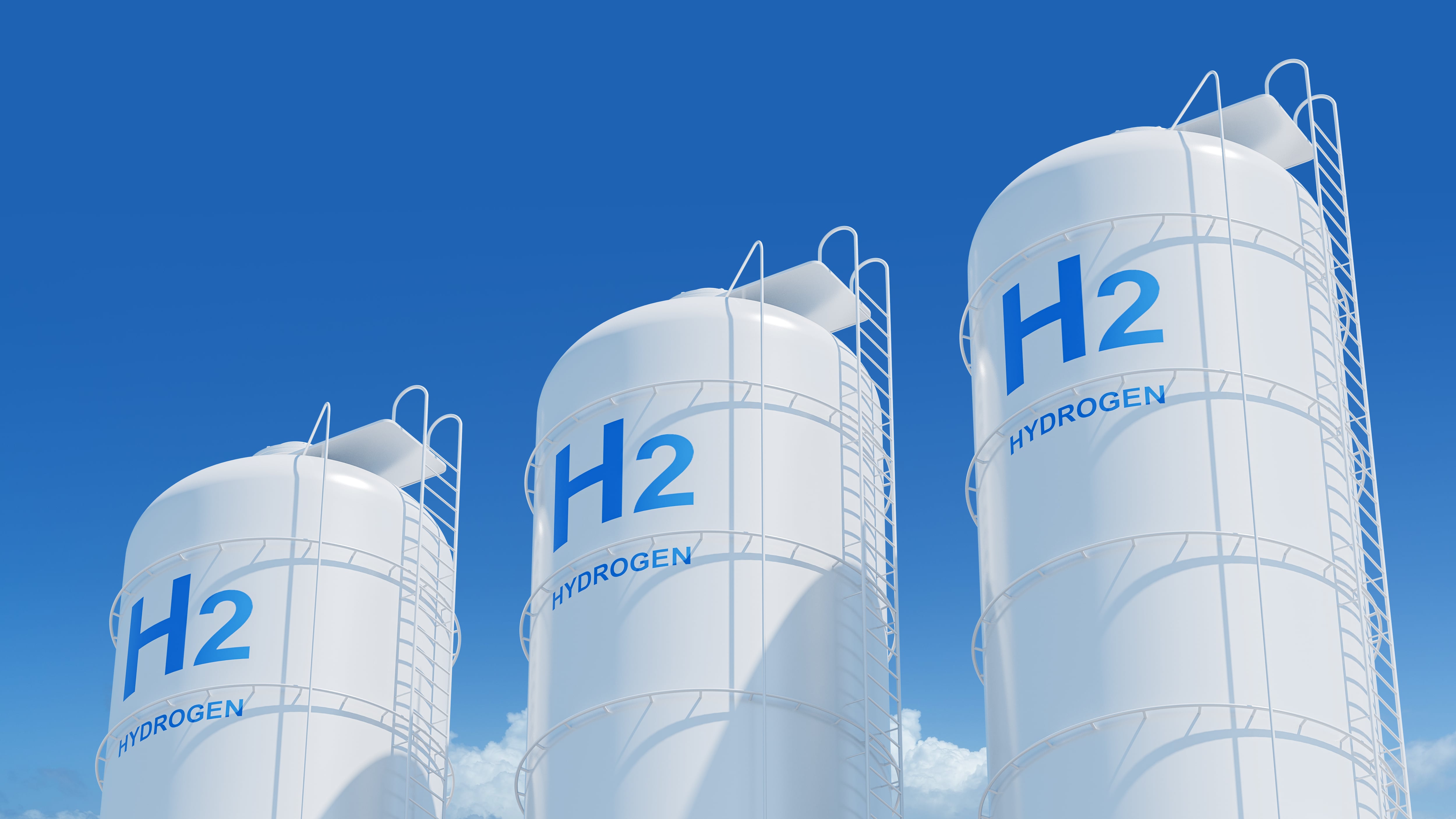 Large storage tanks with H2 and HYDROGEN labels on a blue sky background, representing hydrogen energy storage concept. 3D Rendering